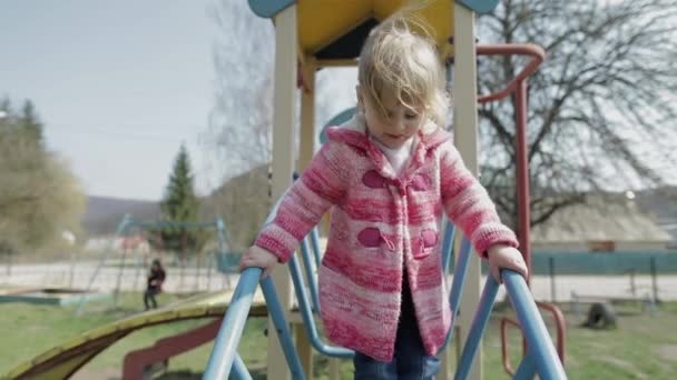 Lustiges nettes Mädchen spielt. fröhliches weibliches Kind hat Spaß auf Spielplatz — Stockvideo