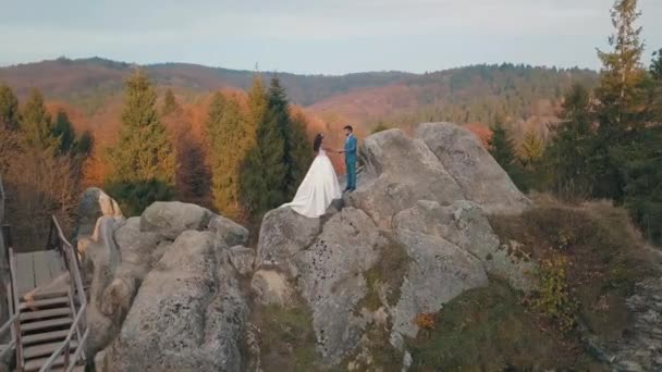 Newlyweds stå på en hög sluttning av berget. Brudgummen och bruden. Arial — Stockvideo