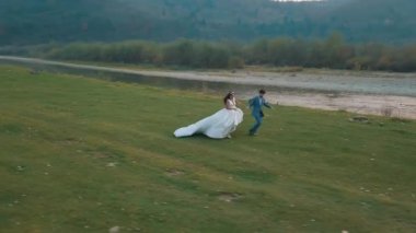 Dağ nehrinin yakınında koşan düğün çifti. Damat ve gelin. Arial görünümü