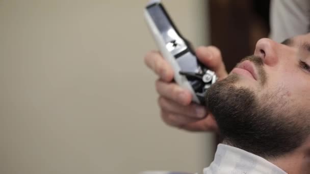 Client avec barbe noire pendant le rasage de barbe dans le salon de coiffure. Groom, masculin — Video