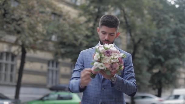 Sposo con la barba nera con bouquet da sposa per strada. Giorno del matrimonio — Video Stock