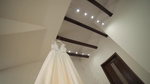 De bruiden jurk hangt onder het plafond. Zeer mooi en elegant. Bruiloft — Stockvideo