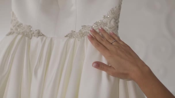 La mano de la novia hermosa toca el vestido de novia. Mujer bonita y bien arreglada — Vídeos de Stock