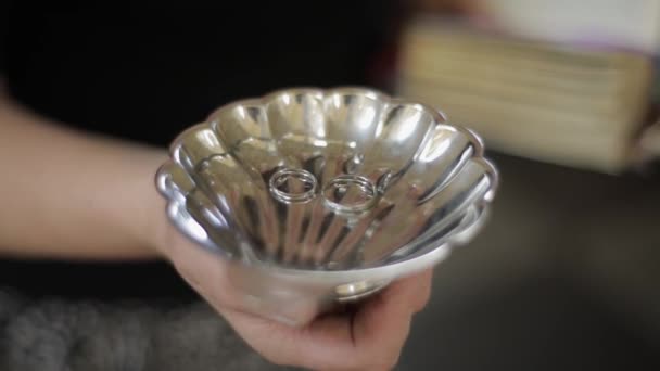 Wedding silver rings lying on shiny church plate. Shining with light. Close-up — Stock Video