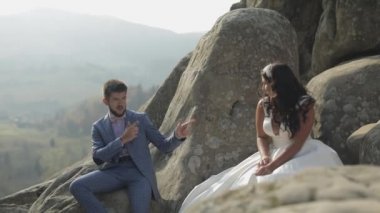 Gelin ile damat dağın yüksek bir eğim üzerinde oturmak. Düğün çifti. Mutlu