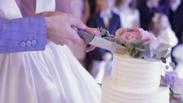 Nevěsta a ženich si střímají svatební dort. Ruce ostříhat kus koláče