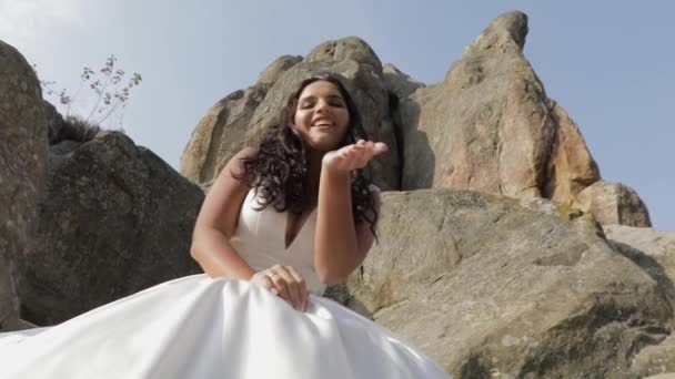 新娘坐在山的高坡上。快乐。跳舞和制作面孔 — 图库视频影像
