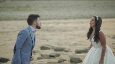 Dağ nehrinin yanında duran düğün çifti. Damat ve gelin yüzler yapma