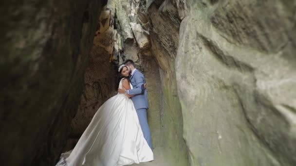 Novio con novia de pie en la cueva de las colinas de montaña. Pareja de boda enamorada — Vídeo de stock