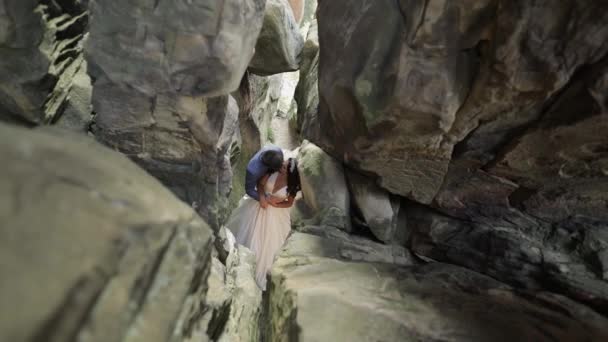 Novio con novia de pie en la cueva de las colinas de montaña. Pareja de boda enamorada — Vídeo de stock