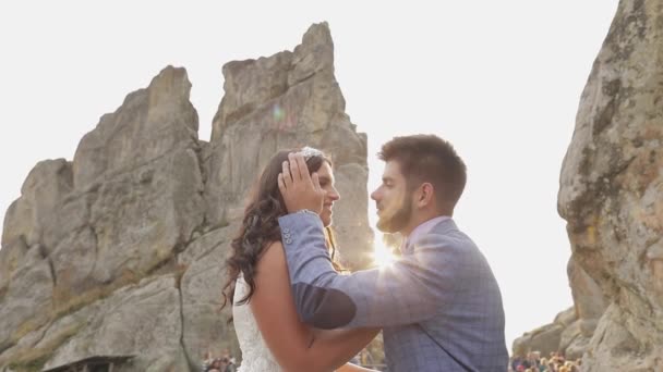 Novio con novia cerca de las colinas de montaña. Pareja de bodas enamorada. Rayos de sol — Vídeos de Stock