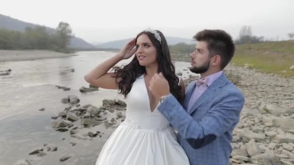 Bröllops paret står nära berget floden. Brudgum och brud kär — Stockvideo