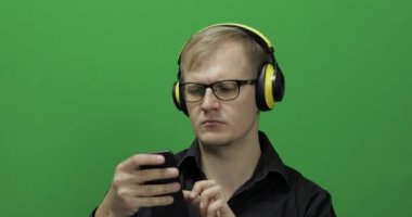 Adam kablosuz sarı kulaklıkla müzik dinliyor ve dans ediyor. Yeşil Ekran