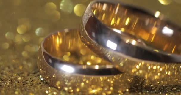 Wedding gols rings lying on shiny glossy surface. Shining with light. Close-up — Stock Video