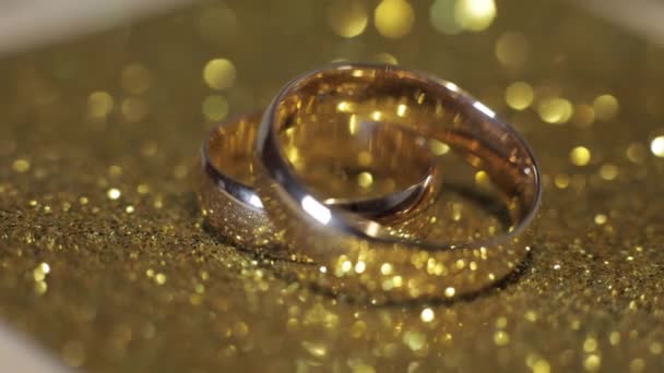 Hochzeitsringe liegen auf glänzender Oberfläche. leuchtet vor Licht. Nahaufnahme — Stockvideo