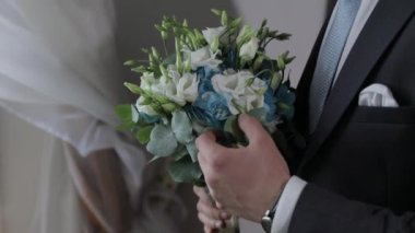 Evde elinde düğün buketi olan damat. Beyaz gömlek, mavi kravat, ceket