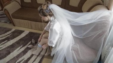 Gece elbisesi içinde güzel ve güzel gelin bacak üzerinde düğün jartiyer giyer