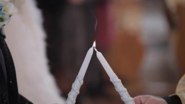 Gelin ve damat kilisede dikilip, ellerinde mumları tutuyor