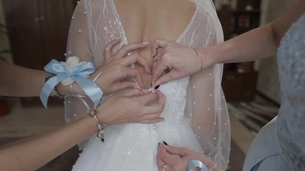Подружка невесты помогает застегнуть молнию свадебного платья для прекрасной невесты в день свадьбы — стоковое видео