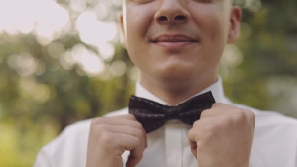 ハンサムな新郎は彼の蝶ネクタイを修正します。クローズアップショット。結婚式の朝. — ストック動画