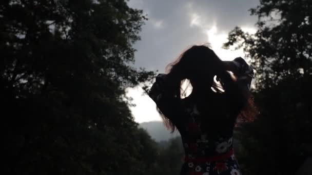 Young woman plays with her hair in sunbeams. Silhouette — Stock Video