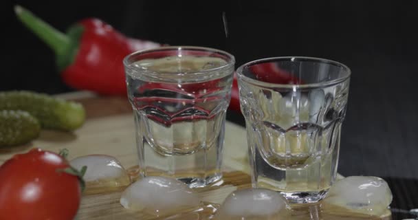 Vierta el vodka de una botella en vasos de chupito. El hombre toma una copa con vodka — Vídeos de Stock