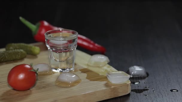 Man zet een glas gevuld met wodka op het houten bord — Stockvideo