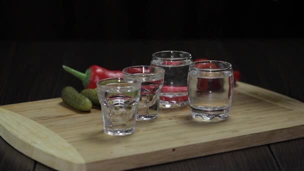 Man neemt een glas gevuld met wodka van het houten bord — Stockvideo