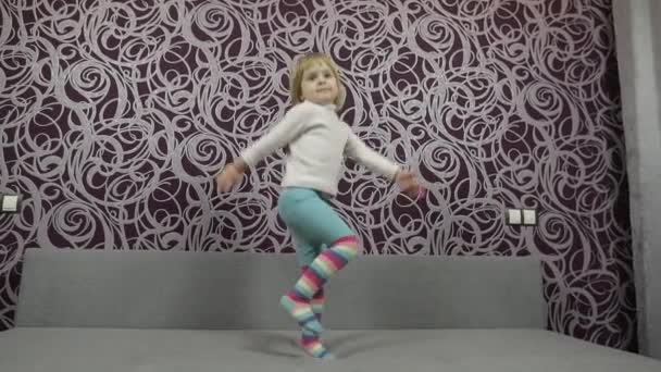 Pequena criança feliz pulando e dançando no sofá e ouvindo música — Vídeo de Stock