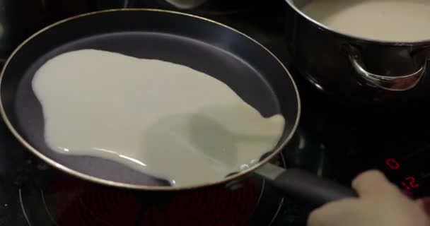 Процесс приготовления самодельных блинчиков. Женщина наливает блинчики на сковородку. — стоковое видео