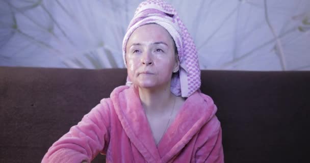 Mujer viendo una película nocturna en la televisión, comiendo palomitas de maíz. Albornoz, máscara facial — Vídeos de Stock