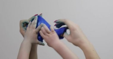 Kadın ve çocuk elleri tatmin edici mavi yapışkan madde oynuyorlar. Stres önleyici