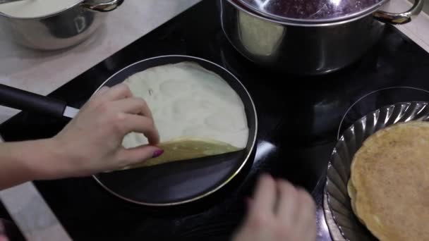 Het proces van het koken van zelfgemaakte pannenkoeken. Vrouw zet pannenkoek in een koekenpan — Stockvideo