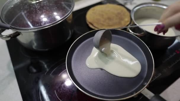 Der Prozess des Kochens hausgemachter Pfannkuchen. Frau gießt Pfannkuchenteig auf Pfanne — Stockvideo