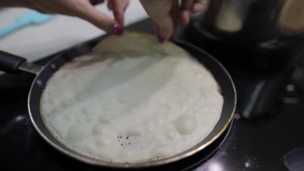 Het proces van het koken van zelfgemaakte pannenkoeken. Vrouw zet pannenkoek in een koekenpan — Stockvideo