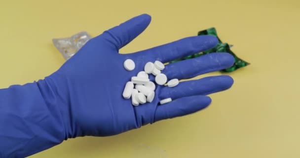 Una gran cantidad de pastillas blancas en la mano vestidas con guante médico estéril de goma — Vídeo de stock