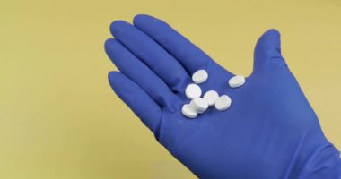 Elinde kauçuk steril tıbbi eldiven giymiş beyaz hapları büyük miktarda