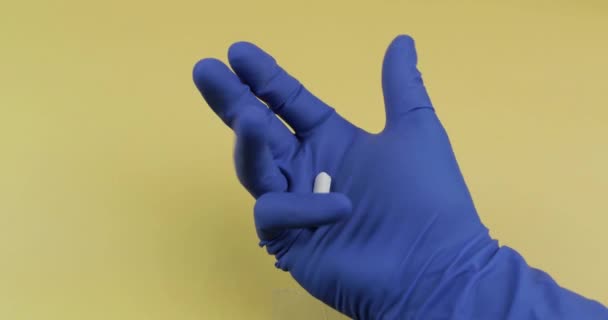 Eine ovale und eine runde weiße Tablette in der Hand, bekleidet mit einem blauen Medizinhandschuh — Stockvideo