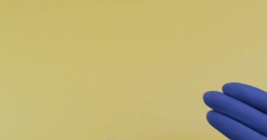 Elinde kauçuk steril tıbbi eldiven giymiş bir yuvarlak beyaz hap