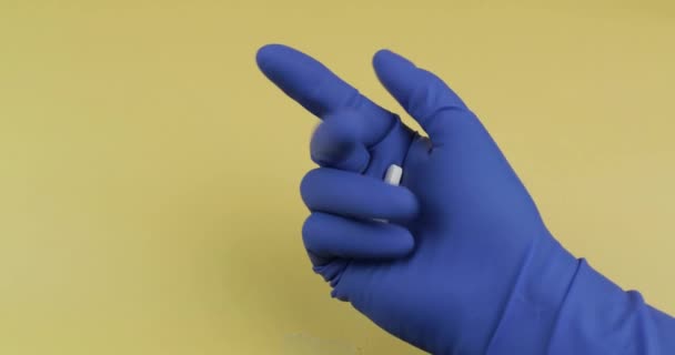 Pilules blanches à la main habillées en gant médical bleu. Femme prend une pilule ronde — Video