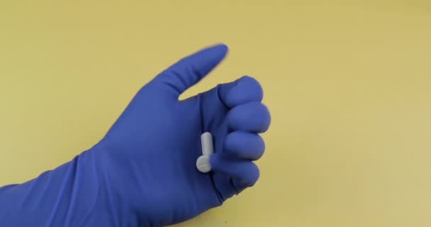 Белые таблетки в руке, одетые в голубую медицинскую перчатку. Женщина принимает одну таблетку — стоковое видео