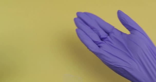 Hand dressed in blue medical glove puts one oval white pill into other hand — Stock Video