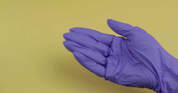 Main habillée en gant médical bleu met une pilule blanche ronde dans l'autre main — Video