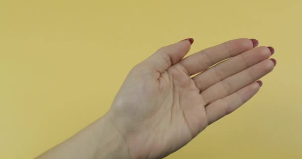 Врач рука в синей медицинской перчатке кладет одну белую таблетку в руку женщине — стоковое видео