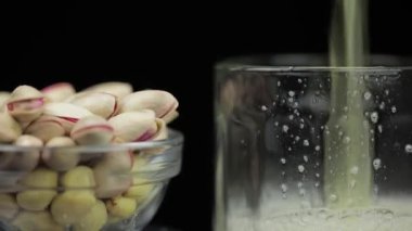 Bira siyah arka plan üzerinde cam içine dökülüyor. Antep fıstığı kase