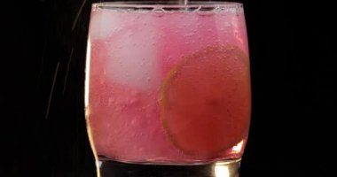 Buz ve kireç ile bir bardak serinletici bir kırmızı içecek kokteyl yapma