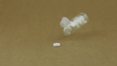 Cam kavanoz düşer ve beyaz yuvarlak haplar düşer. Yavaş çekim