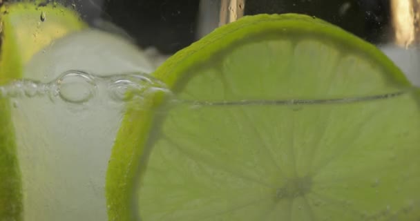Освежающий напиток наливают в стакан со льдом и лаймом. Крупный план — стоковое видео