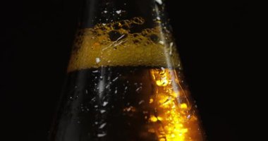 Siyah bir arka plan üzerinde soğuk bira şişesi. Yavaşça dönüyor. Kondens