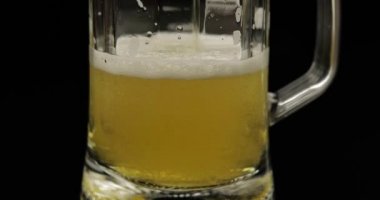 Bir bardağa soğuk altın ışıklı bira dökmek. Zanaat bira kabarcıklar ve köpük yapma